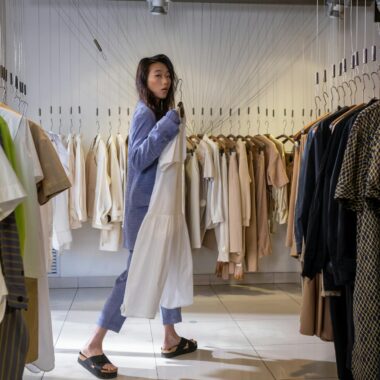Stylish young woman shopping in a chic clothing boutique, selecting trendy outfits.