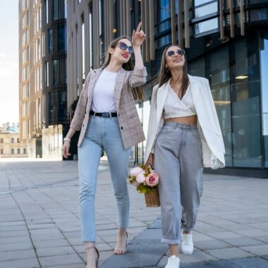 Two stylish women in sunglasses walking outdoors, embracing fashion trends.