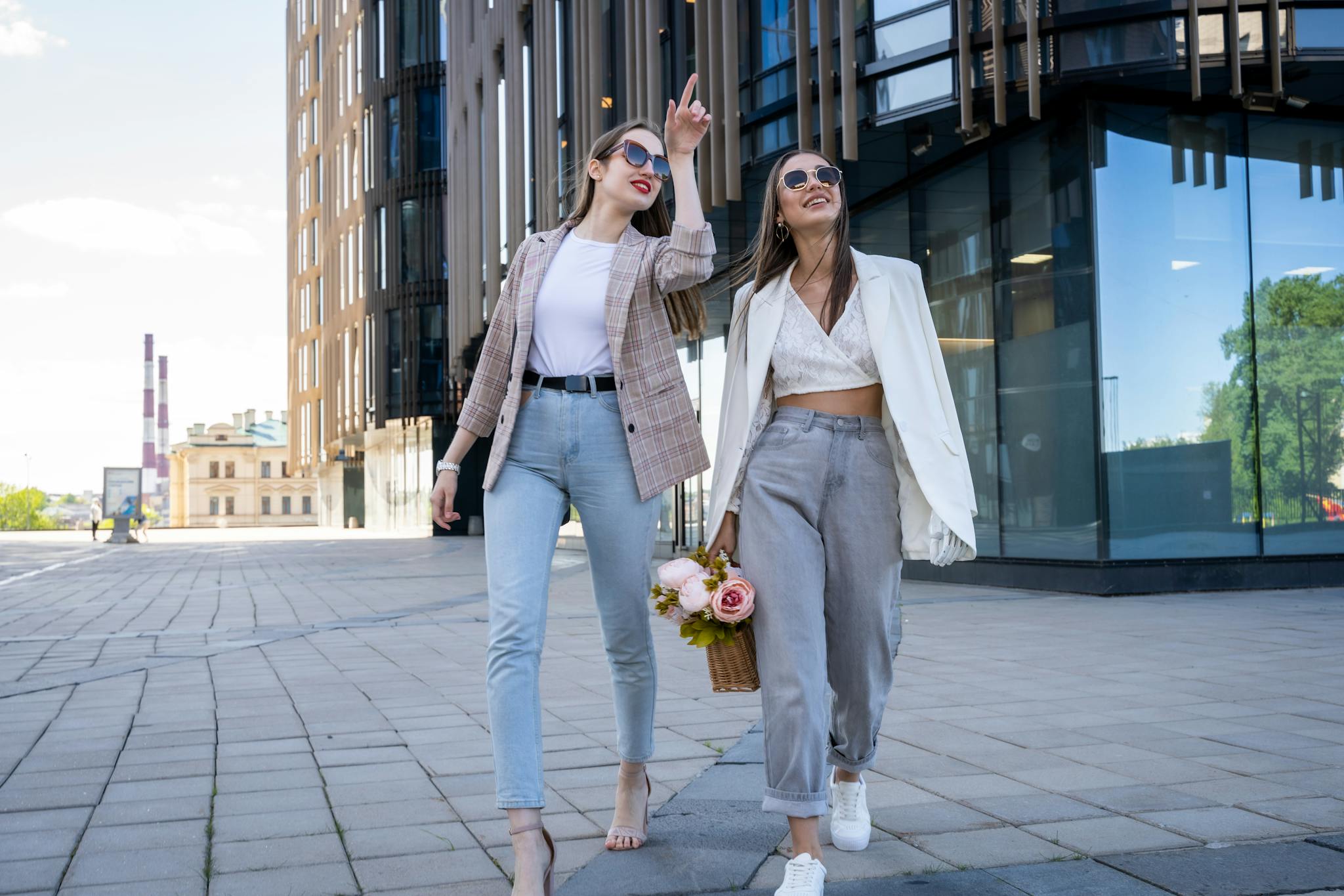 Two stylish women in sunglasses walking outdoors, embracing fashion trends.